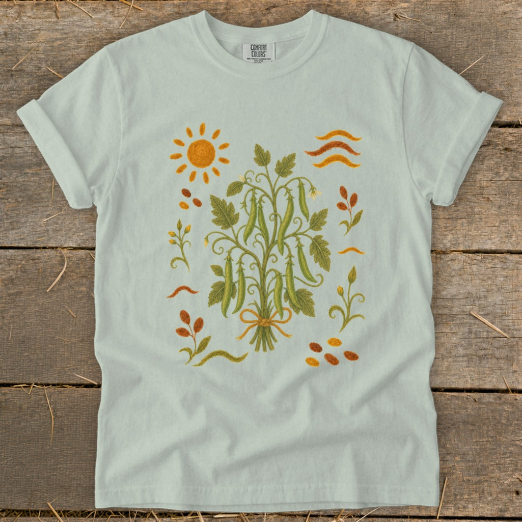 Light blue t-shirt with a botanical illustration of pea pods and a sun.