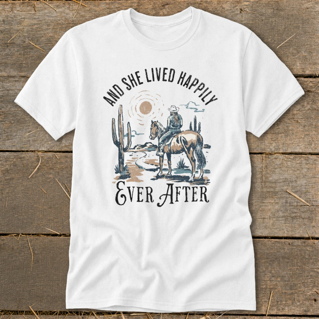 White t-shirt with desert scene graphic and text "And She Lived Happily Ever After".