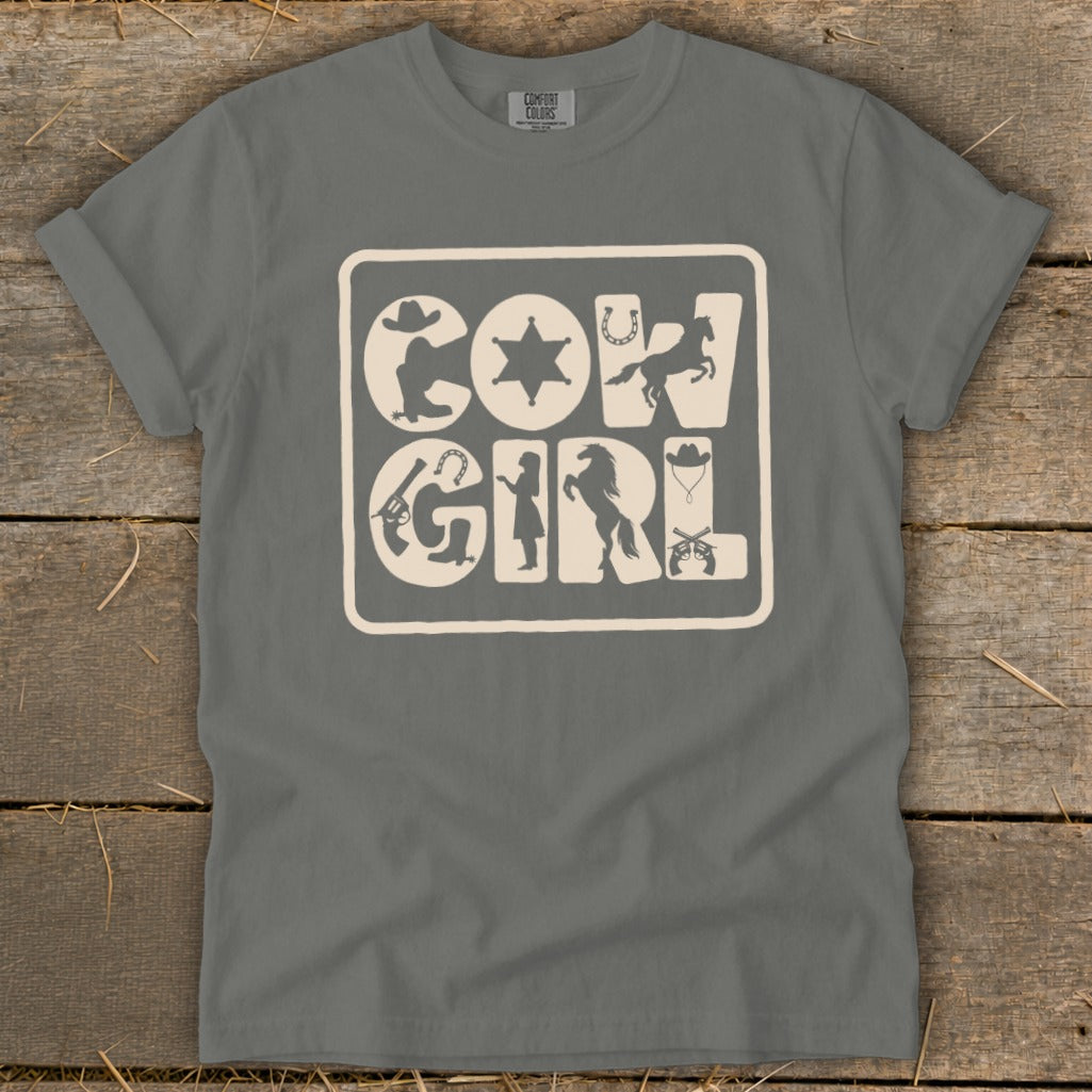 "Cowgirl" text graphic with western motifs on a gray t-shirt.