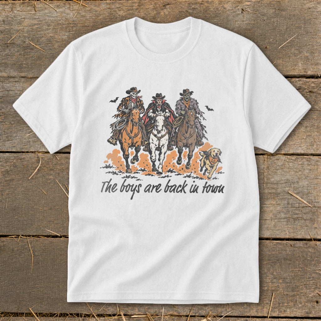 White t-shirt graphic of three cowboys on horses and a dog with text "The boys are back in town."