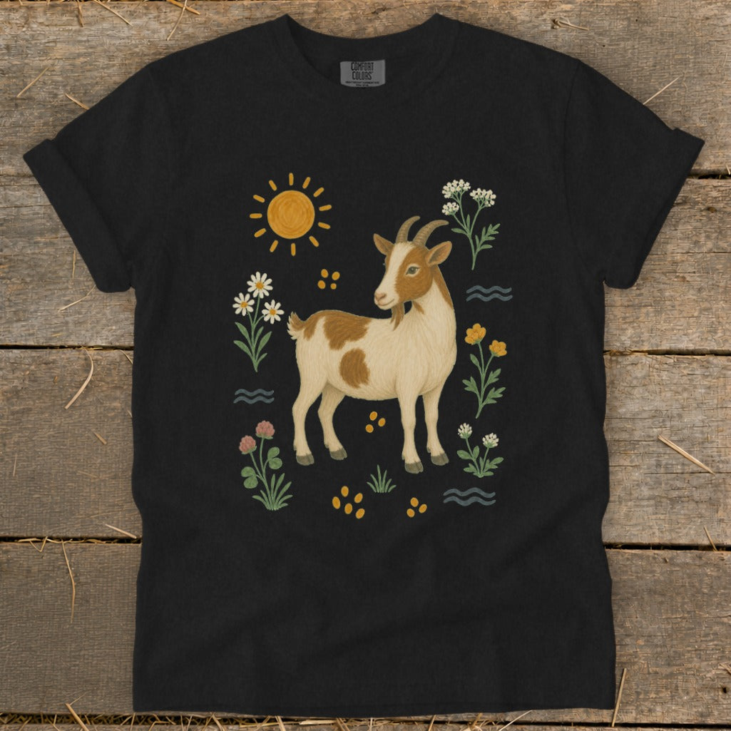 Black t-shirt featuring a brown and white goat surrounded by flowers, sun, and water elements.