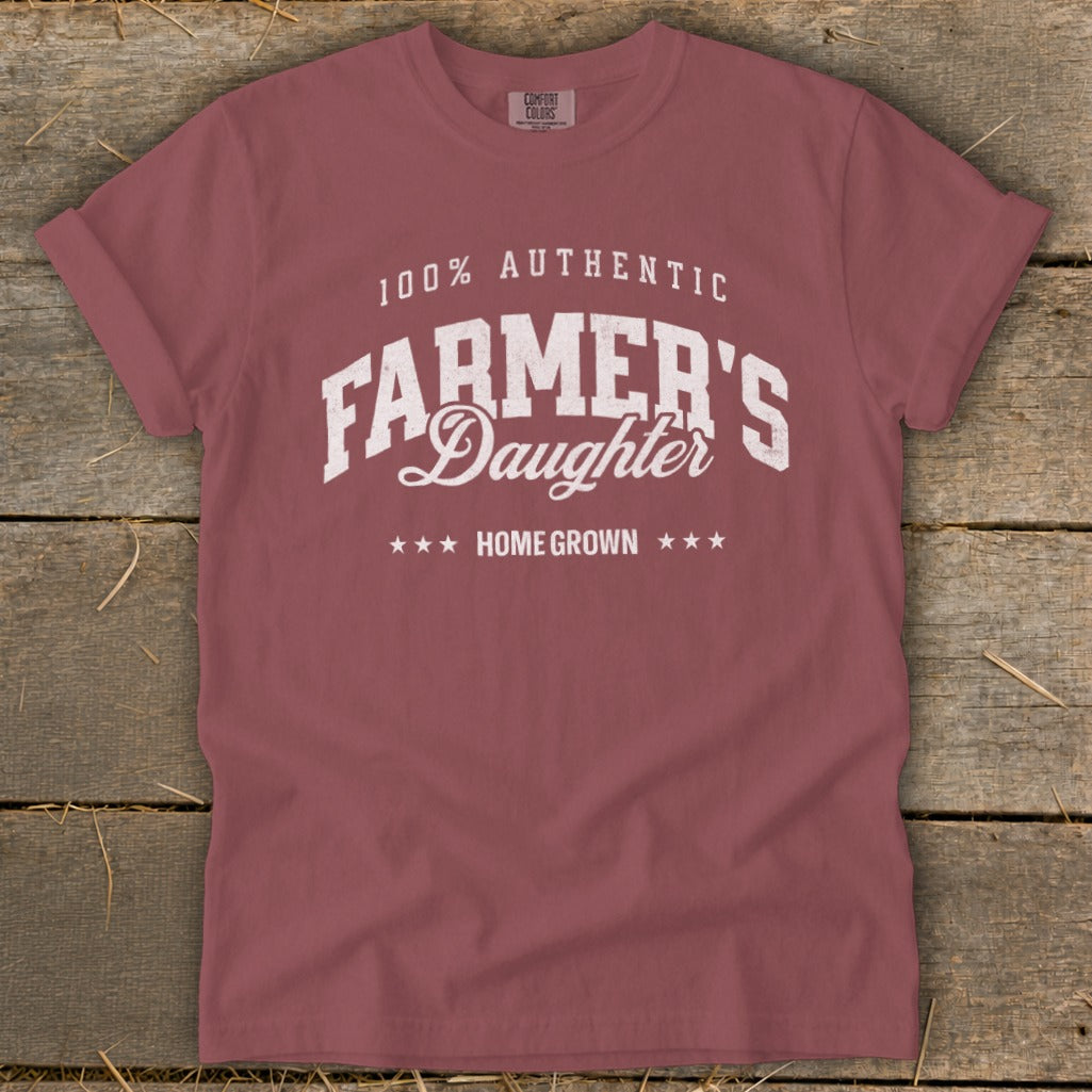 Rose-colored t-shirt with white text: "100% AUTHENTIC FARMER'S Daughter HOME GROWN".