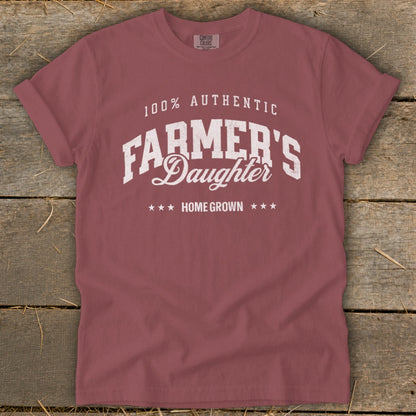 Rose-colored t-shirt with white text: "100% AUTHENTIC FARMER'S Daughter HOME GROWN".