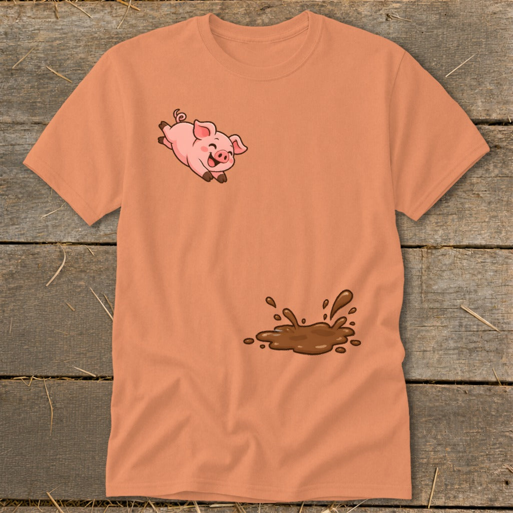Orange t-shirt with a cartoon pig jumping over a mud puddle.