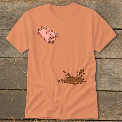 Orange t-shirt with a cartoon pig jumping over a mud puddle.