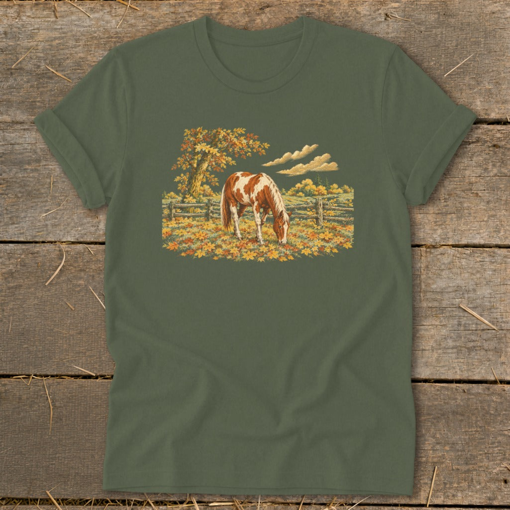 Brown and white horse grazing in a fall meadow with a wooden fence and autumn trees.