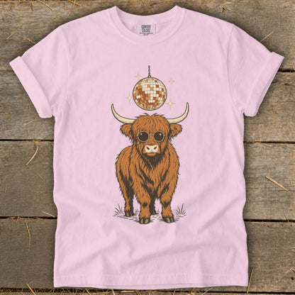 Highland cow wearing sunglasses under a disco ball on a pink t-shirt.