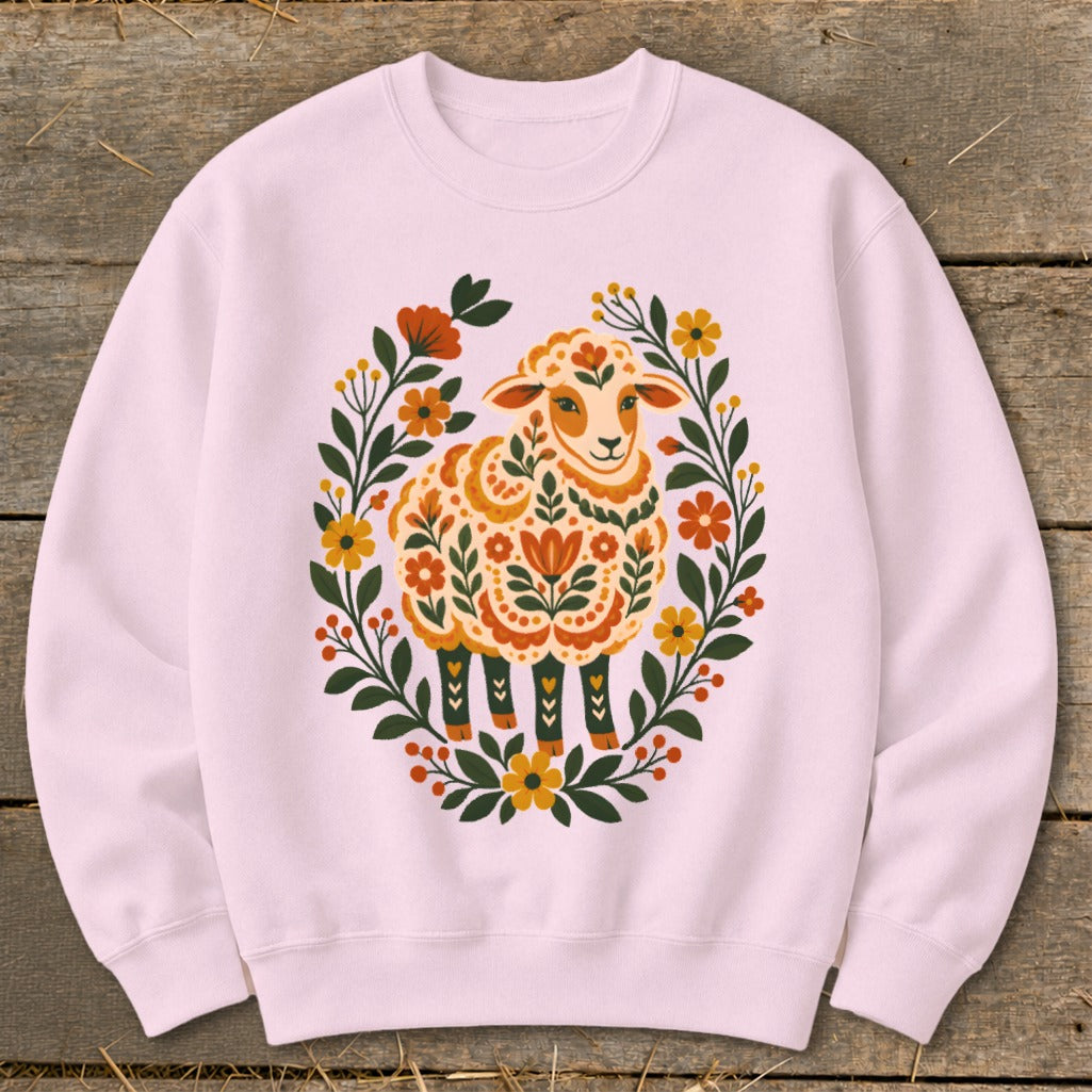Pink crewneck sweatshirt with a decorative sheep surrounded by floral wreath.
