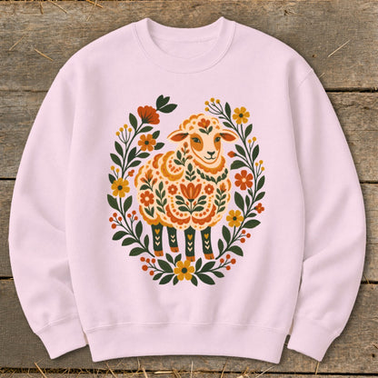 Pink crewneck sweatshirt with a decorative sheep surrounded by floral wreath.