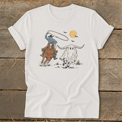 Skeleton cowboy on horse lassos a longhorn ghost under a full moon.