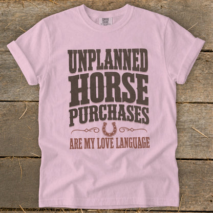 Pink t-shirt with "Unplanned Horse Purchases Are My Love Language" text and horseshoe graphic.