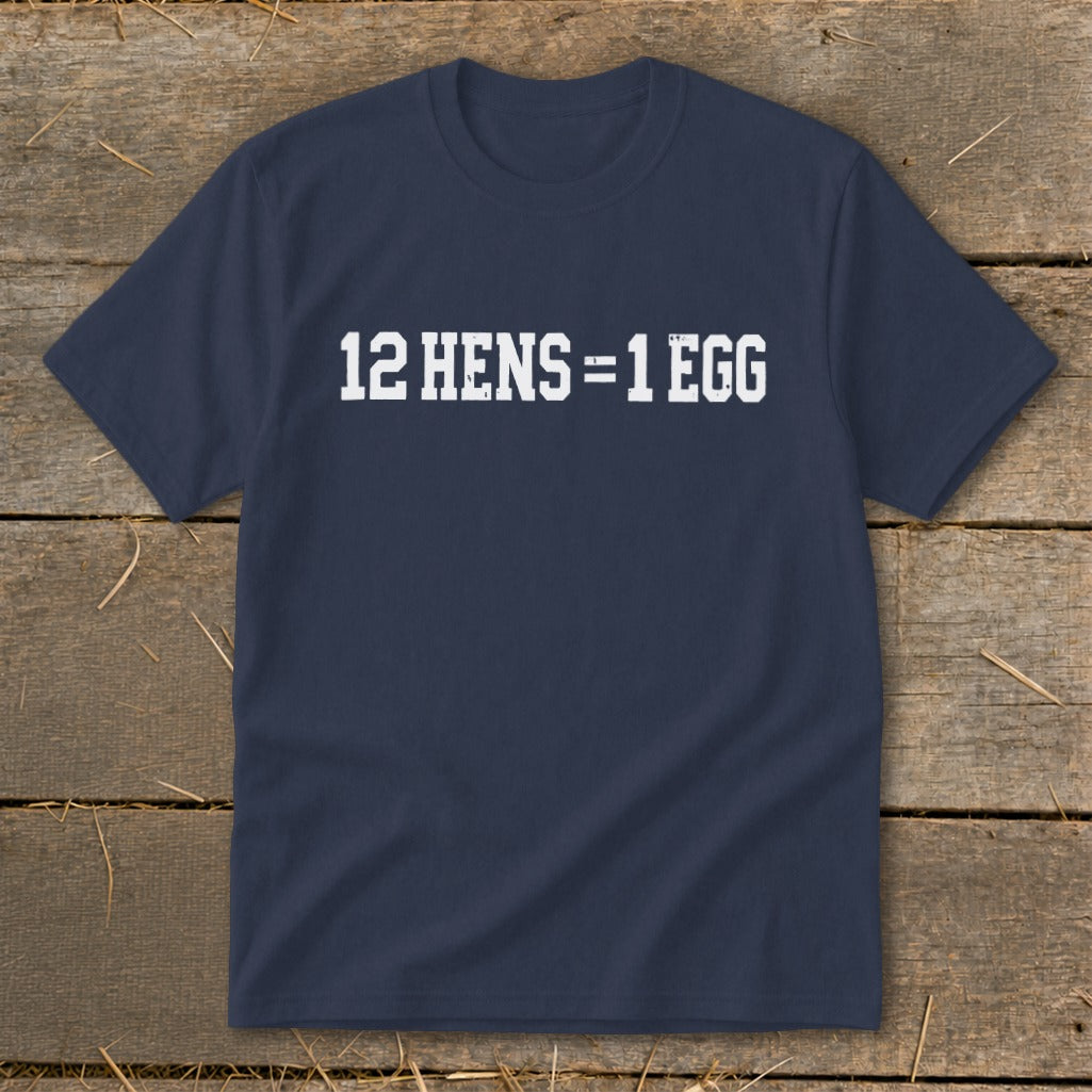 Dark blue crew neck t-shirt with white distressed text reading 12 HENS = 1 EGG on a wooden background.