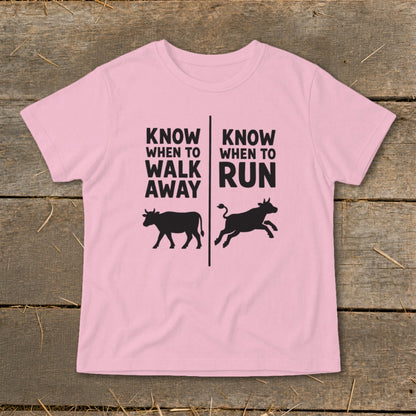 Pink t-shirt with text and black cow silhouettes showing walking and running.