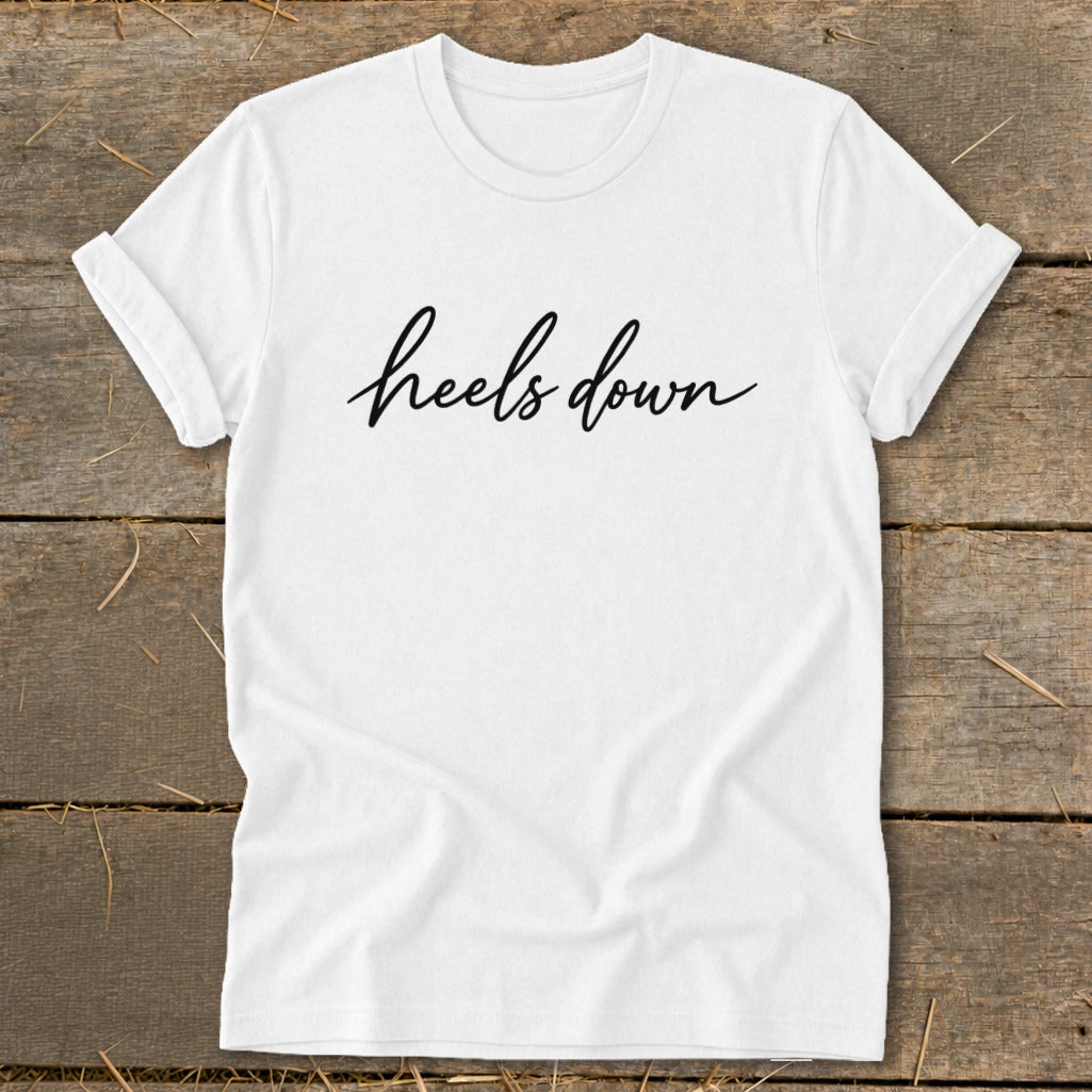 White t-shirt with black cursive text that says "heels down".
