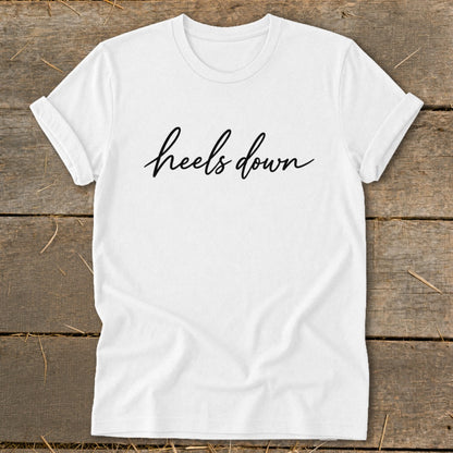 White t-shirt with black cursive text that says "heels down".