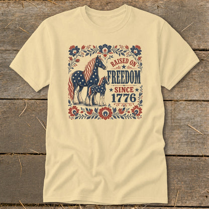 Cream t-shirt with horses and "Raised on Freedom Since 1776" text.