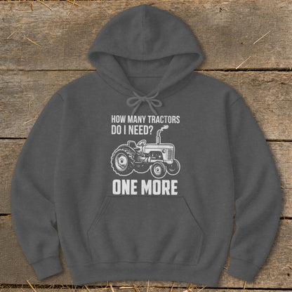 Dark gray hoodie with a graphic of a tractor and text reading "How Many Tractors Do I Need? One More."