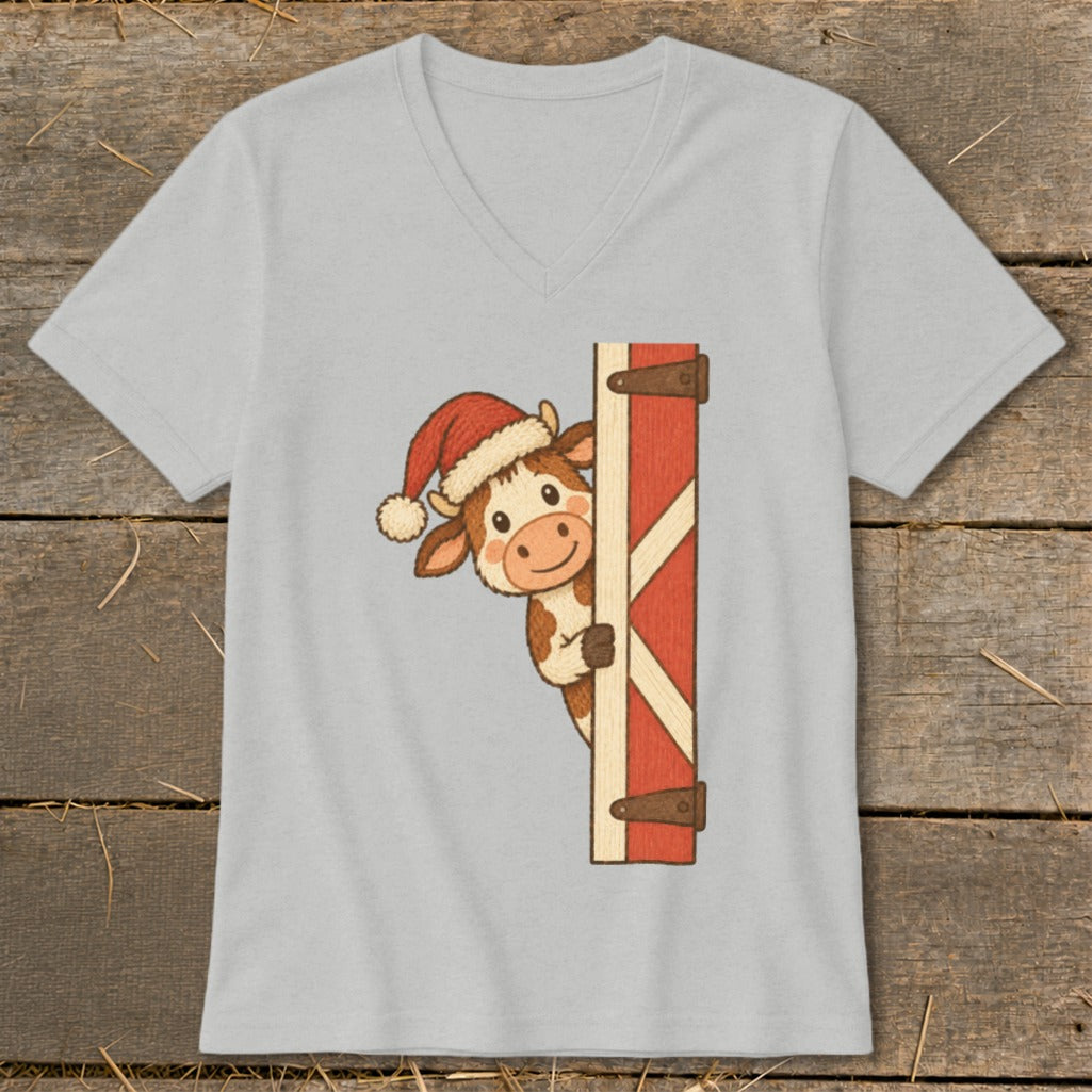 Cartoon cow wearing a Santa hat peeking around a barn door.
