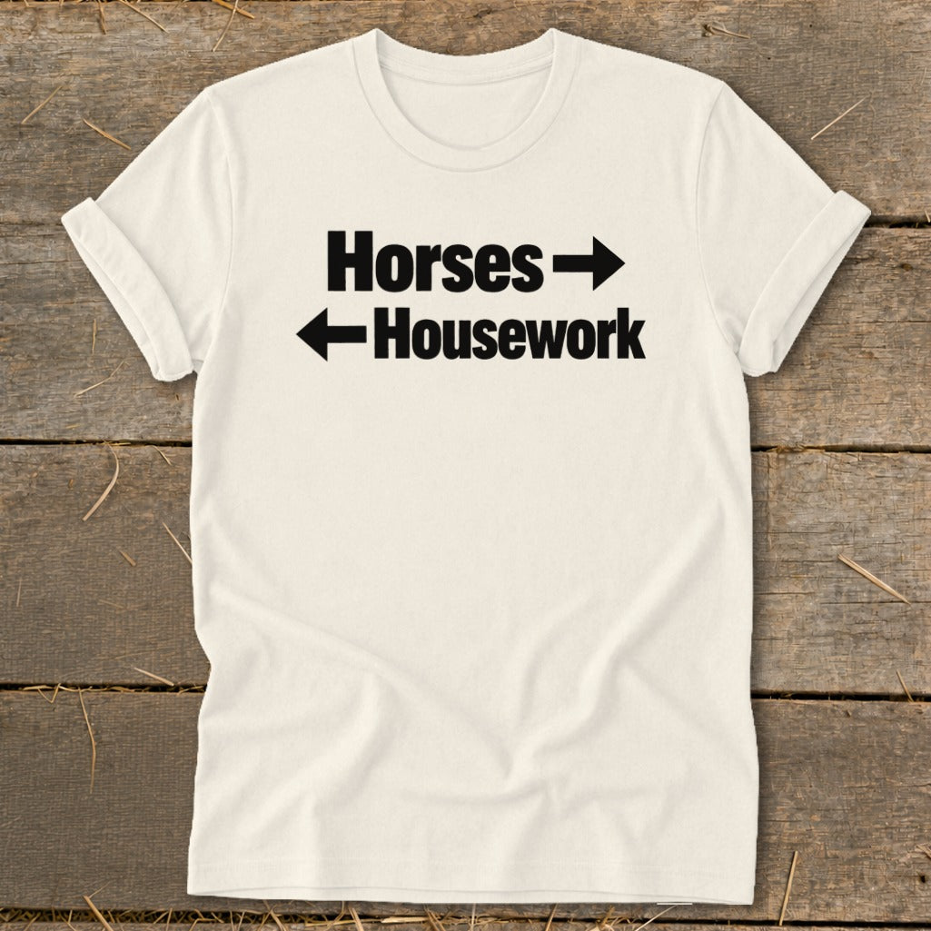 Cream-colored crewneck t-shirt with black text reading Horses and Housework, separated by directional arrows.