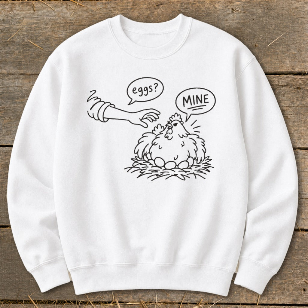 White sweatshirt with cartoon chicken protecting eggs, text says "eggs?" and "MINE".