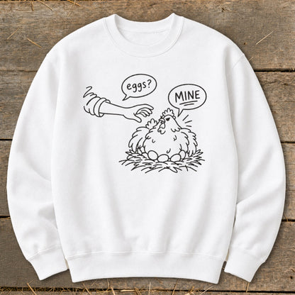 White sweatshirt with cartoon chicken protecting eggs, text says "eggs?" and "MINE".