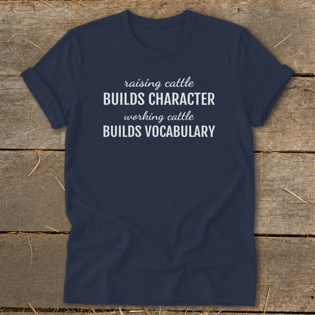 Navy t-shirt with white text reading "raising cattle BUILDS CHARACTER working cattle BUILDS VOCABULARY."