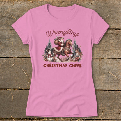 Pink t-shirt with Santa riding a horse, a snowman, and a reindeer. "Wrangling Christmas Cheer" text.