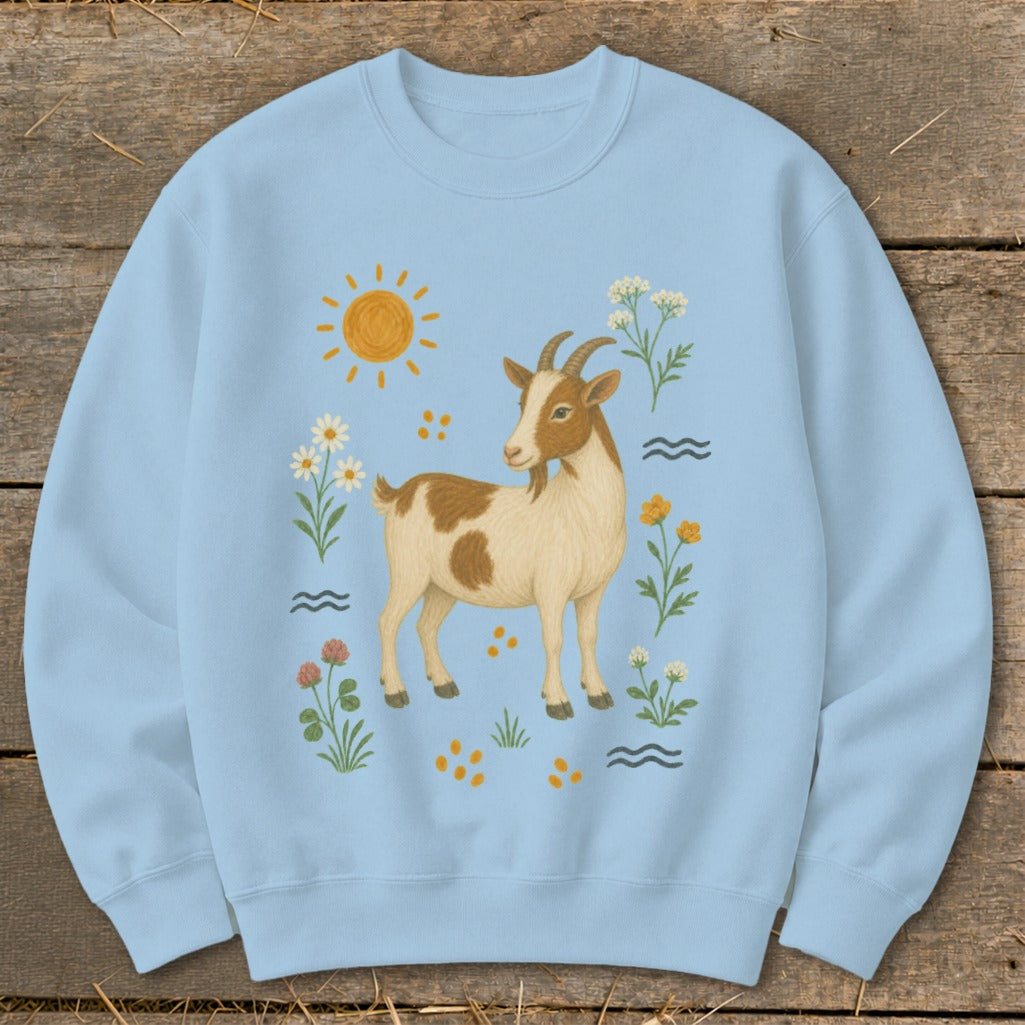 Light blue sweatshirt with a brown and white goat surrounded by flowers and sun.