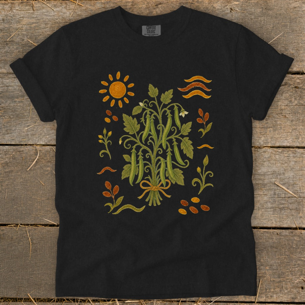 Black t-shirt with a colorful illustration of a pea plant, sun, and seeds.