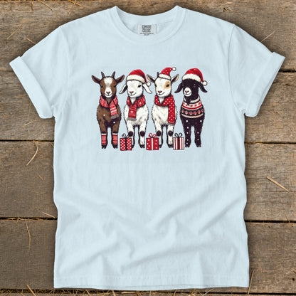 Four goats in Santa hats and festive scarves stand in front of gift boxes.