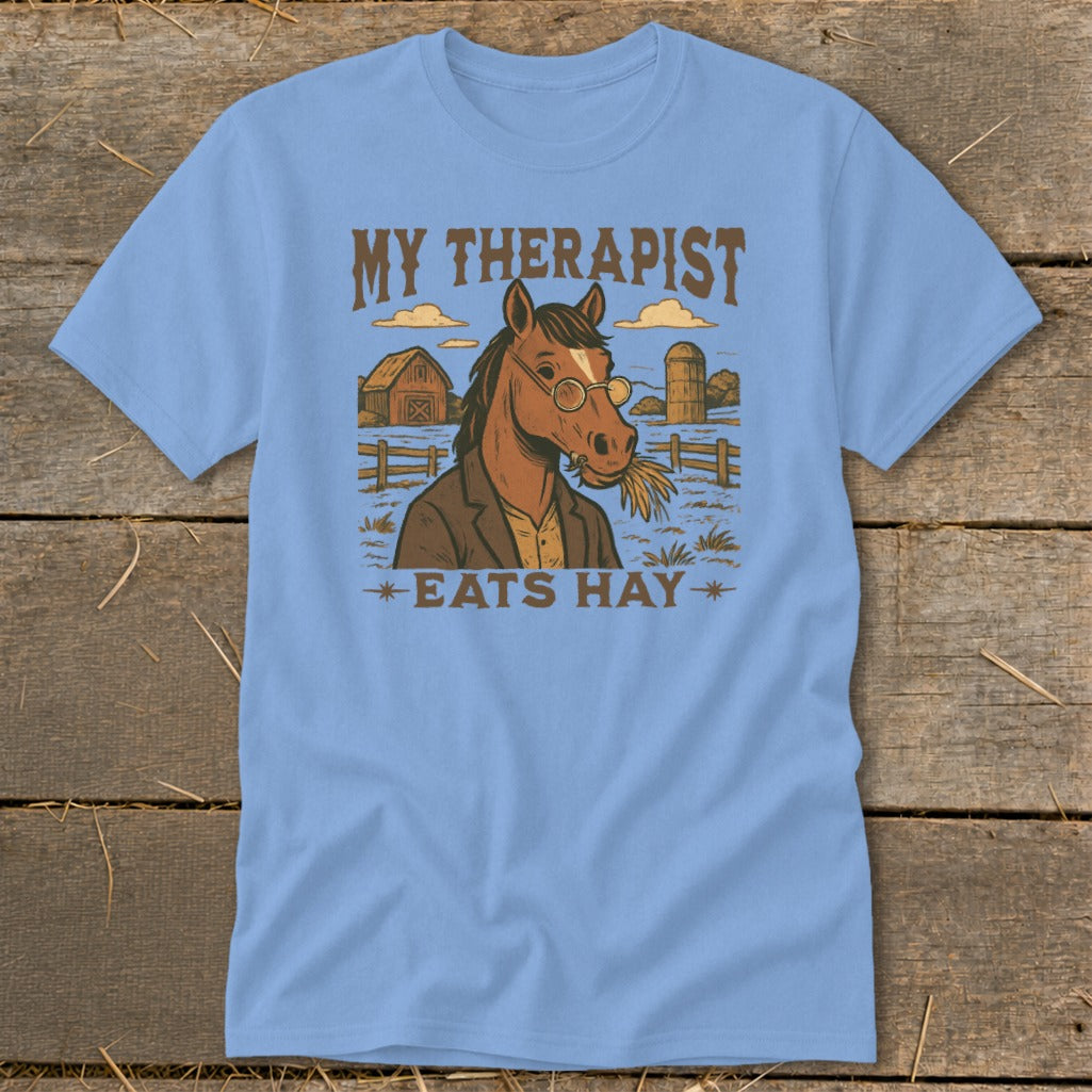 Light blue t-shirt with a horse wearing glasses and eating hay, with text "MY THERAPIST EATS HAY".