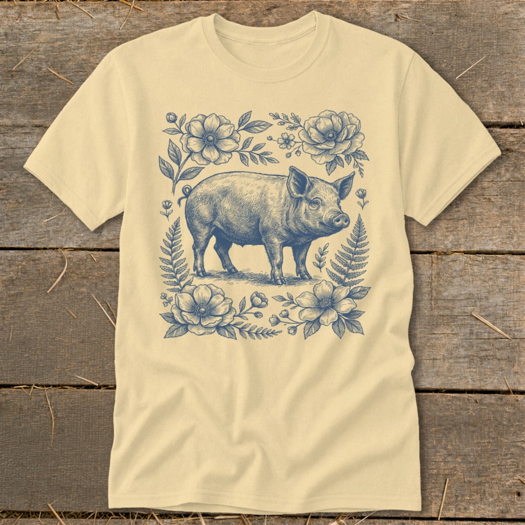 Pig illustration surrounded by flowers and ferns on a cream t-shirt.