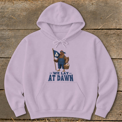 Light purple hoodie with chicken graphic holding flag and basket, text "WE LAY AT DAWN".