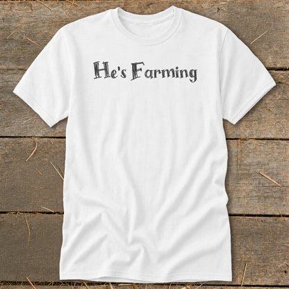 White t-shirt with distressed black text reading "He's Farming."