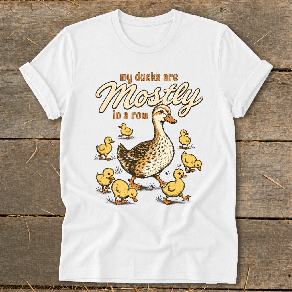 White t-shirt with illustration of a mother duck and ducklings, with text "my ducks are Mostly in a row".