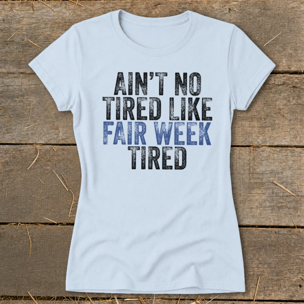 Light blue t-shirt with text: "AIN'T NO TIRED LIKE FAIR WEEK TIRED."