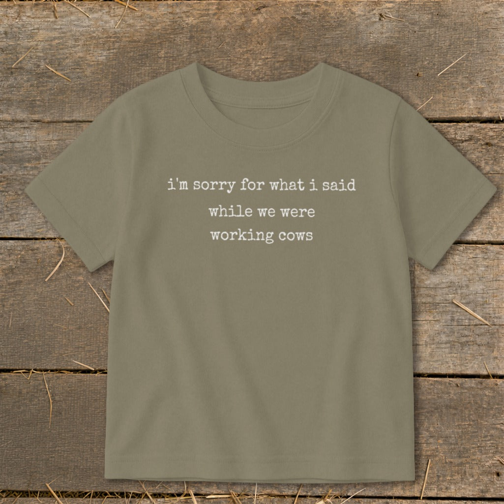 Olive green t-shirt with white text that says "i'm sorry for what i said while we were working cows".
