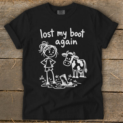 Black t-shirt featuring white line art of a sad person and a cow looking at a muddy boot next to text reading "lost my boot again."
