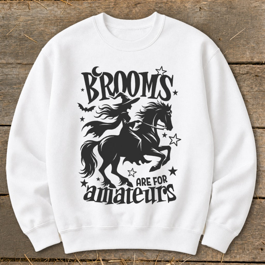 White sweatshirt with black graphic of witch on horse and text "BROOMS ARE FOR amateurs".