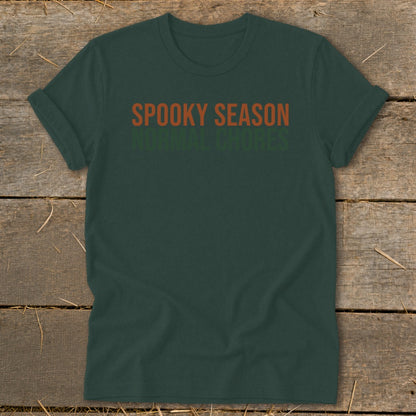 Dark green t-shirt with orange and green text reading "SPOOKY SEASON NORMAL CHORES."