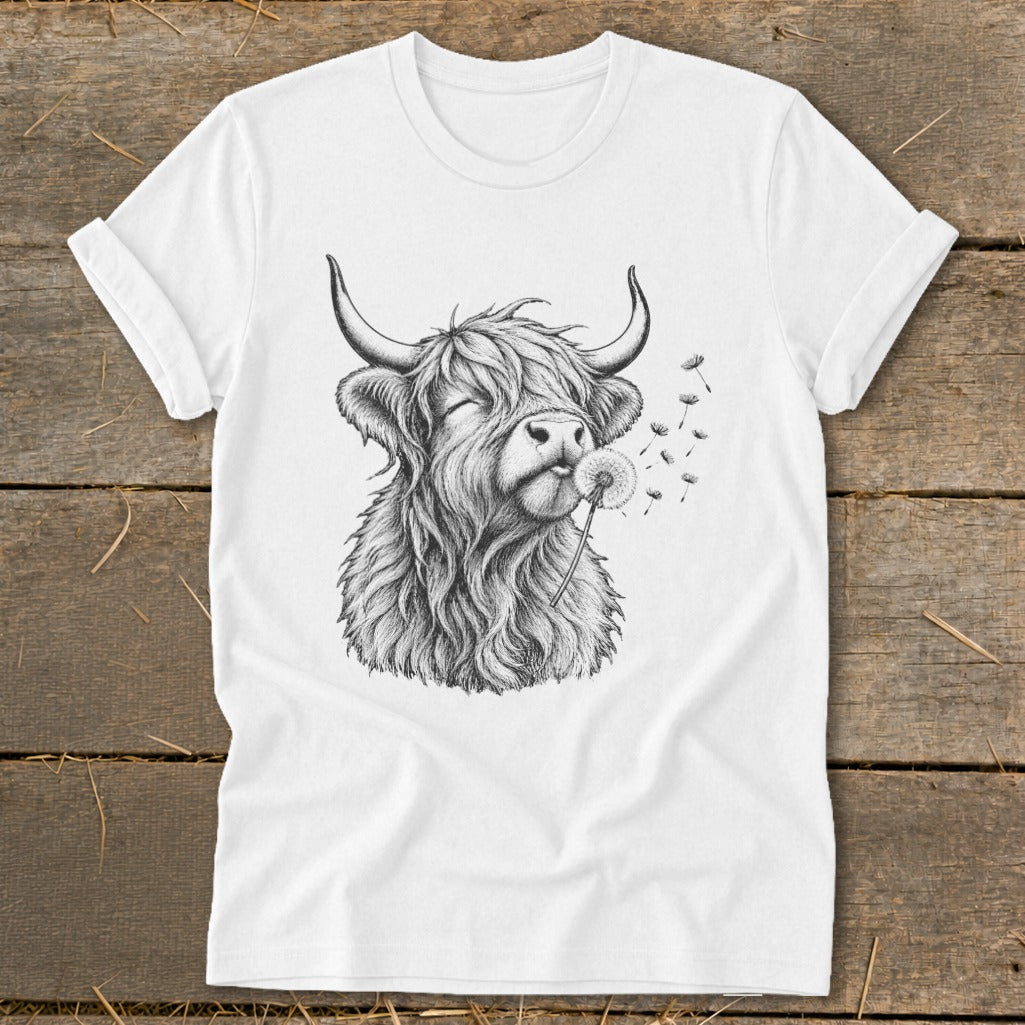 White t-shirt featuring a black and white sketch of a Highland cow blowing dandelions.
