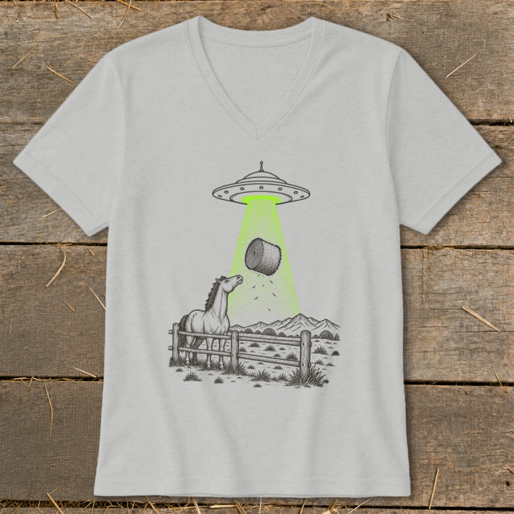 UFO abducting hay bale over a horse in a fenced field with mountains.