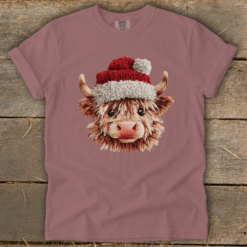 Highland cow wearing a Santa hat with fluffy trim and pom-pom.