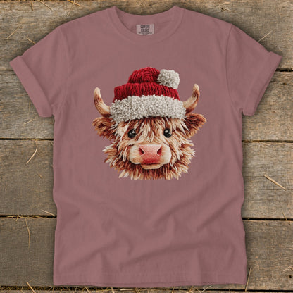 Highland cow wearing a Santa hat with fluffy trim and pom-pom.