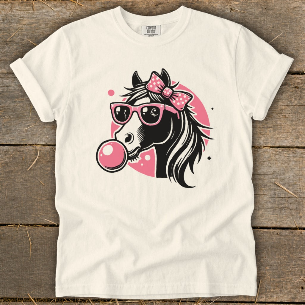 White t-shirt with black horse graphic wearing pink sunglasses and bow, blowing pink bubblegum.