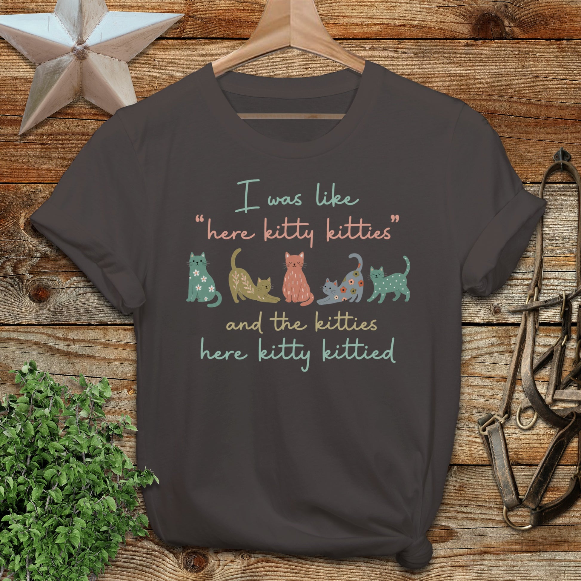 T-shirt with "here kitty kitties" text and colorful cartoon cats.