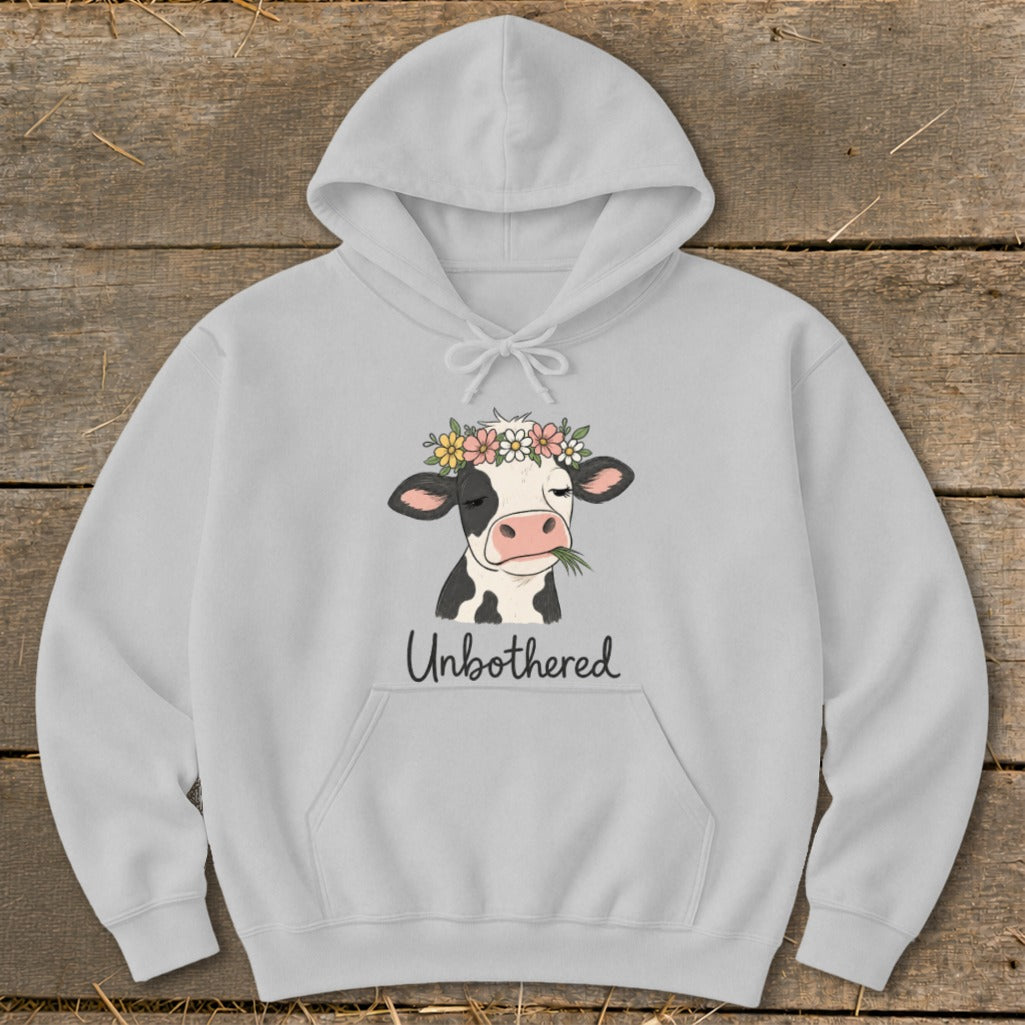 Grey hoodie with a black and white cow wearing a flower crown and eating grass, text "Unbothered".