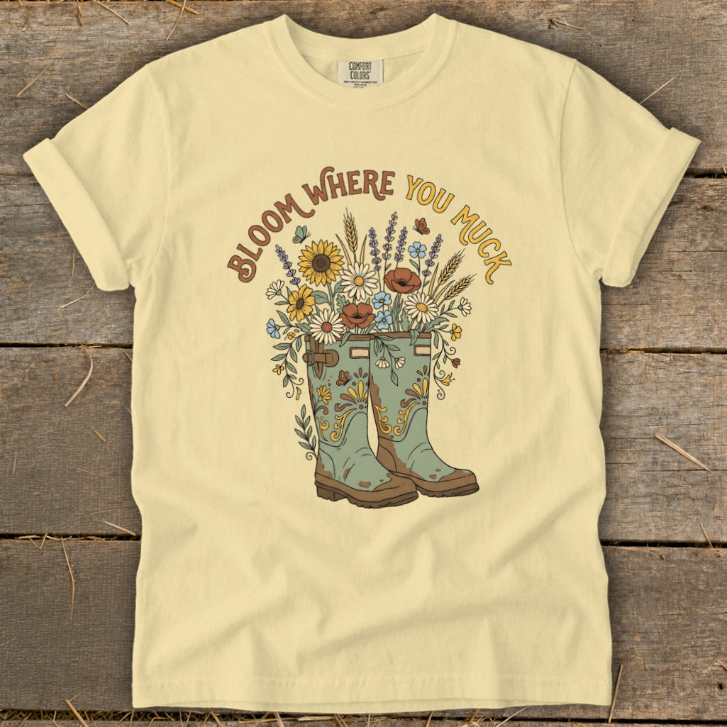Yellow t-shirt with "Bloom Where You Muck" text and floral boots graphic.