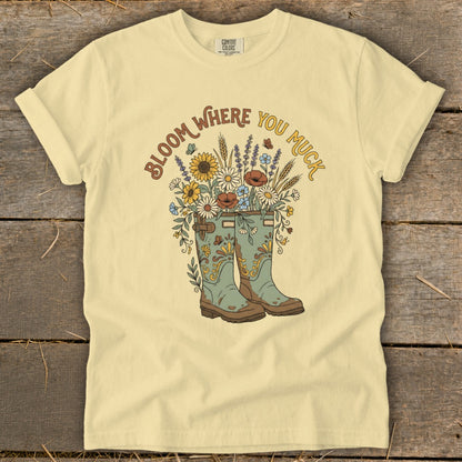 Yellow t-shirt with "Bloom Where You Muck" text and floral boots graphic.