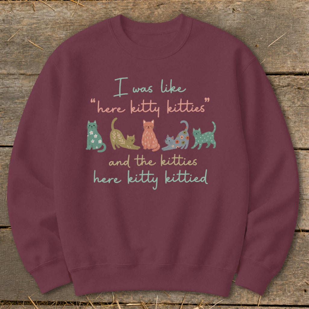 Burgundy sweatshirt with text "I was like 'here kitty kitties' and the kitties here kitty kittied" and illustrations of cats.